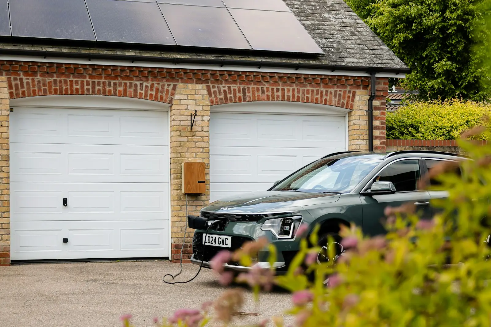 Elektrische auto op de oprit voor een garage met zonnepanelen op het dak